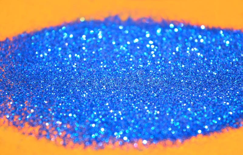 Blurry background of blue glitter sparkles on orange surface