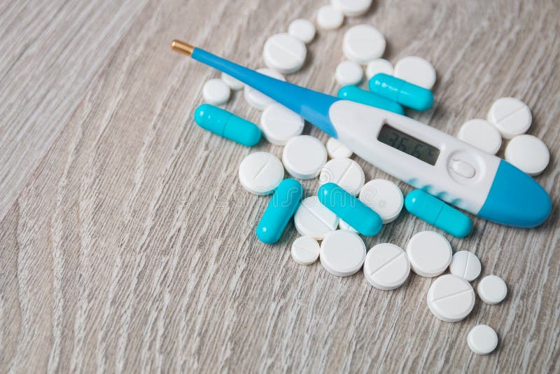 Blå och vit läkarbehandling, preventivpillerar, vitaminer, kapslar, termometer från ovannämnt på grå träbakgrund Alla för influen arkivbilder Blå och vit läkarbehandling, preventivpillerar, vitaminer, kapslar, termometer från ovannämnt på grå träbakgrund Alla för influen arkivbilder