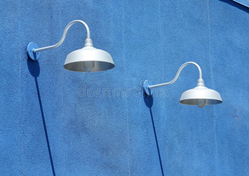 Blue stucco wall with light fixtures and shadows in daytime. Blue stucco wall with light fixtures and shadows in daytime