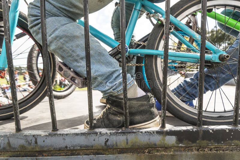 Close up color image of a bmx rider on a blue colored bike wearing blue denim jeans at the top of a ramp. Close up color image of a bmx rider on a blue colored bike wearing blue denim jeans at the top of a ramp.