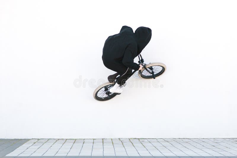 BMX-Reiter fährt Fahrrad auf die weiße Wand Junger Mann tut Tricks auf BMX stockfotografie BMX-Reiter fährt Fahrrad auf die weiße Wand Junger Mann tut Tricks auf BMX stockfotografie