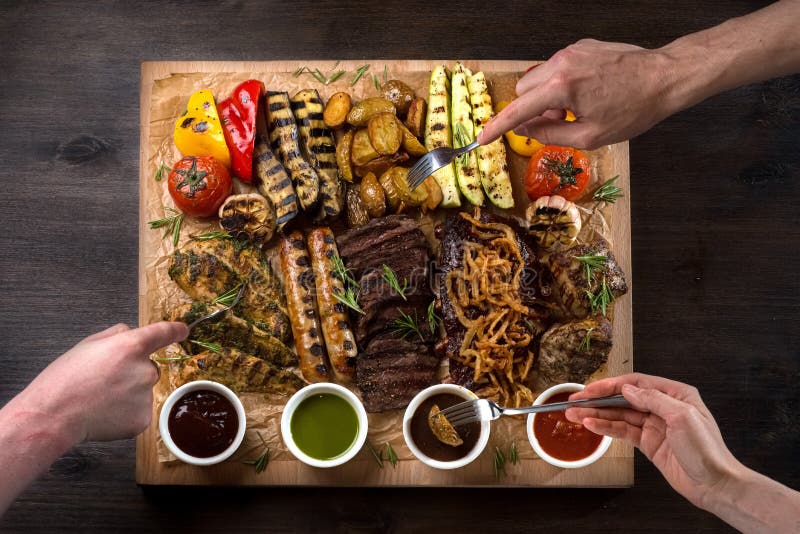 A board with grilled appetizers and sauces. Grilled vegetables and meat snacks, sausages, chicken fillets, pork and beef stock images A board with grilled appetizers and sauces. Grilled vegetables and meat snacks, sausages, chicken fillets, pork and beef stock images