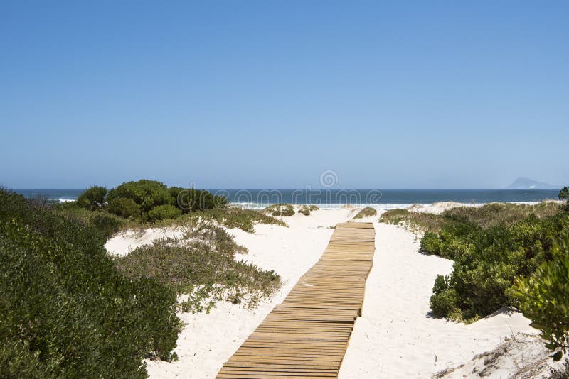 Boardwalk to the sea. Wooden planks over white sand to Atlantic Ocean, South Africa