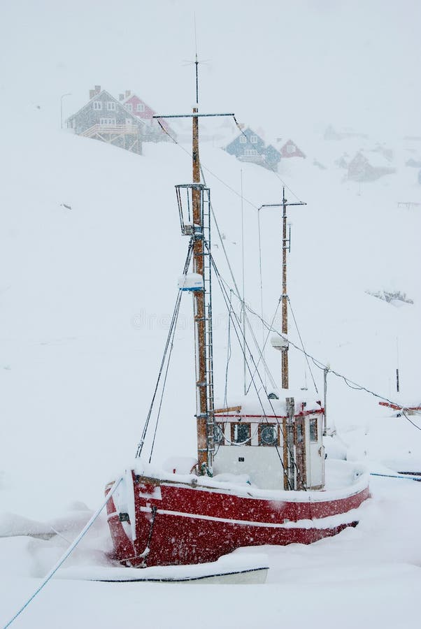 A snowed up red boat being stuck in the ice