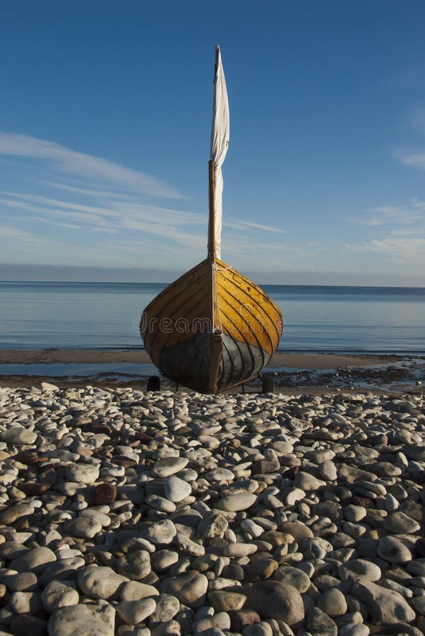 Dřevěná plachetnice na břeh na kamenité pláži.
