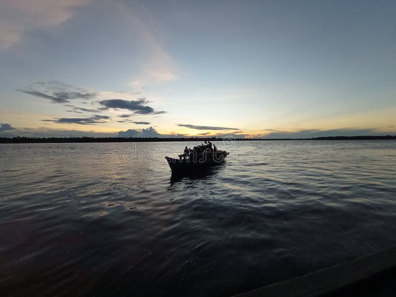 a boat or commonly called kelotok, is crossing the Mentaya Borneo river, the photo was taken in the afternoon