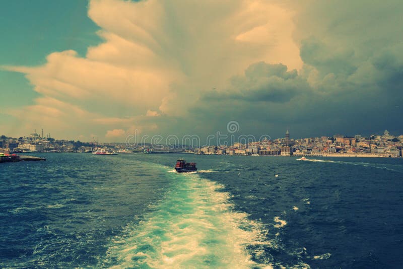 Boat in the sea with the buildings of the city in the background on a cloudy day.