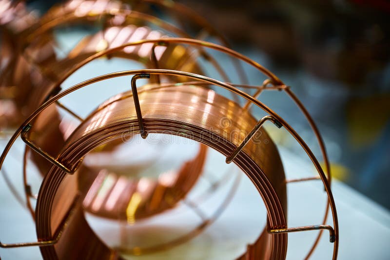 Shiny brass welding wire coil on table in maintenance supplies store closeup. Copper cable for welding machines. Hardware shop product. Shiny brass welding wire coil on table in maintenance supplies store closeup. Copper cable for welding machines. Hardware shop product