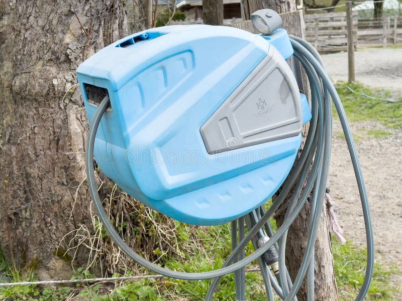Bobine da giardino azzurro montate a parete in posizione esterna vicino agli alberi fotografie stock