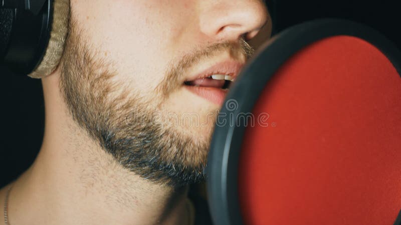 Boca de cantante masculino cantando en estudio de sonido Hombre irreconocible grabando nueva canción El tipo con barba canta al m