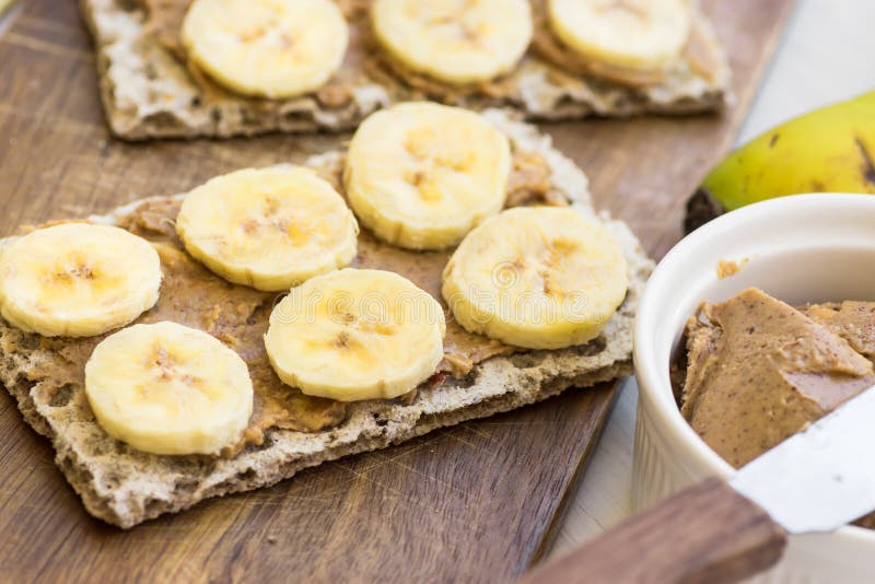 Bocado sano del vegano con el biscote curruscante escandinavo del centeno, la mantequilla de cacahuete hecha en casa y rebanadas imágenes de archivo libres de regalías Bocado sano del vegano con el biscote curruscante escandinavo del centeno, la mantequilla de cacahuete hecha en casa y rebanadas imágenes de archivo libres de regalías