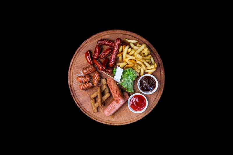 Bocados de la cerveza fijados Salchichas asadas a la parrilla y patatas fritas servidas con el tomate y la salsa del Bbq foto de archivo Bocados de la cerveza fijados Salchichas asadas a la parrilla y patatas fritas servidas con el tomate y la salsa del Bbq foto de archivo