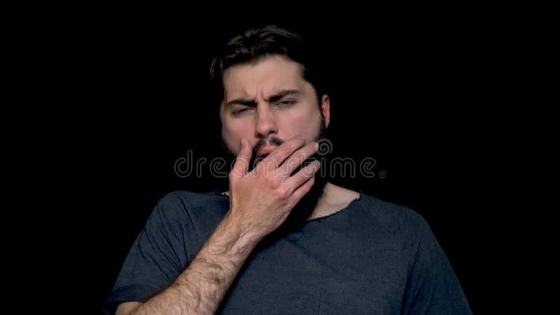Bocejo farpado novo sonolento do homem, fechando sua boca com a mão, isolada no fundo Vista de bocejo do indivíduo farpado imagem de stock royalty free Bocejo farpado novo sonolento do homem, fechando sua boca com a mão, isolada no fundo Vista de bocejo do indivíduo farpado imagem de stock royalty free