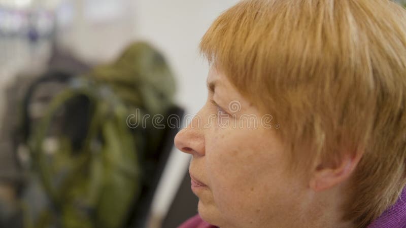 Bocznego widoku portret starej kobiety obsiadanie przy lotniskiem i czekać na wycieczką