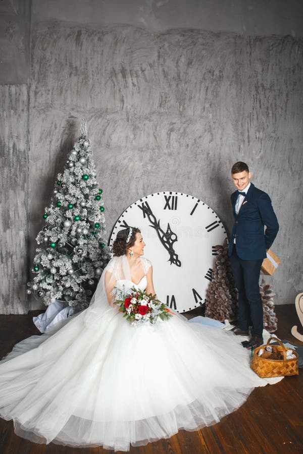 Boda del invierno Amantes novia y novio en la decoración de la Navidad Novio que sostiene el regalo Sorpresa romántica para la Na foto de archivo Boda del invierno Amantes novia y novio en la decoración de la Navidad Novio que sostiene el regalo Sorpresa romántica para la Na foto de archivo