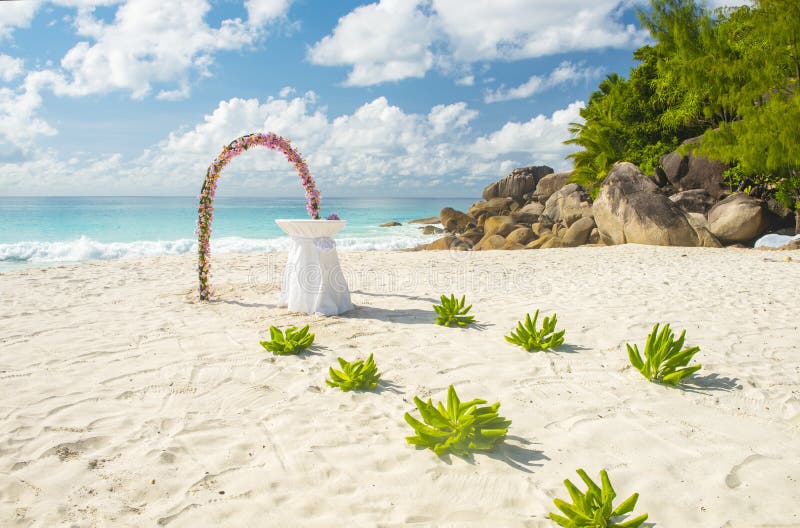 Floral garland and a white table as wedding decorations on a tropical beach Anse Georgette on Praslin island in the Seychelles. Floral garland and a white table as wedding decorations on a tropical beach Anse Georgette on Praslin island in the Seychelles