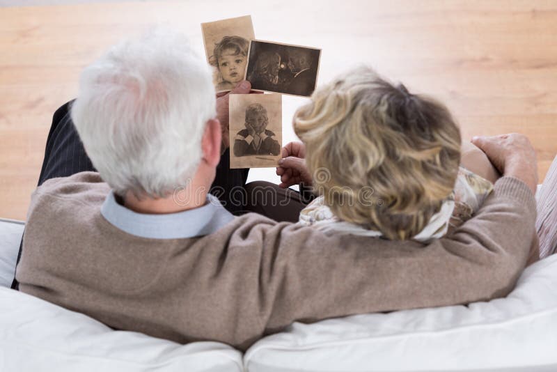 Senior marriage sitting on the sofa and looking at old photos. Senior marriage sitting on the sofa and looking at old photos