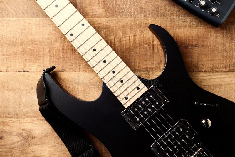 Body and fretboard of modern electric guitar on rustic wooden background.