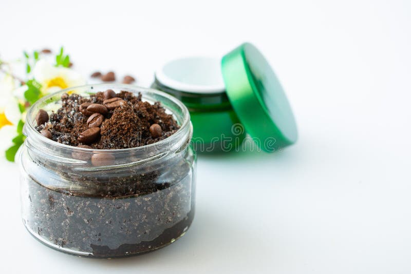 Body scrub made from coffee and sugar in a glass jar and face cream on a white background. The concept of home spa care and beauty.