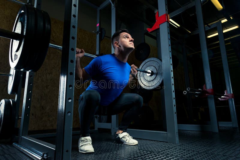 Bodybuilder in einem blauen T-Shirt mit einem Barbell in der Turnhalle lizenzfreie stockfotografie Bodybuilder in einem blauen T-Shirt mit einem Barbell in der Turnhalle lizenzfreie stockfotografie