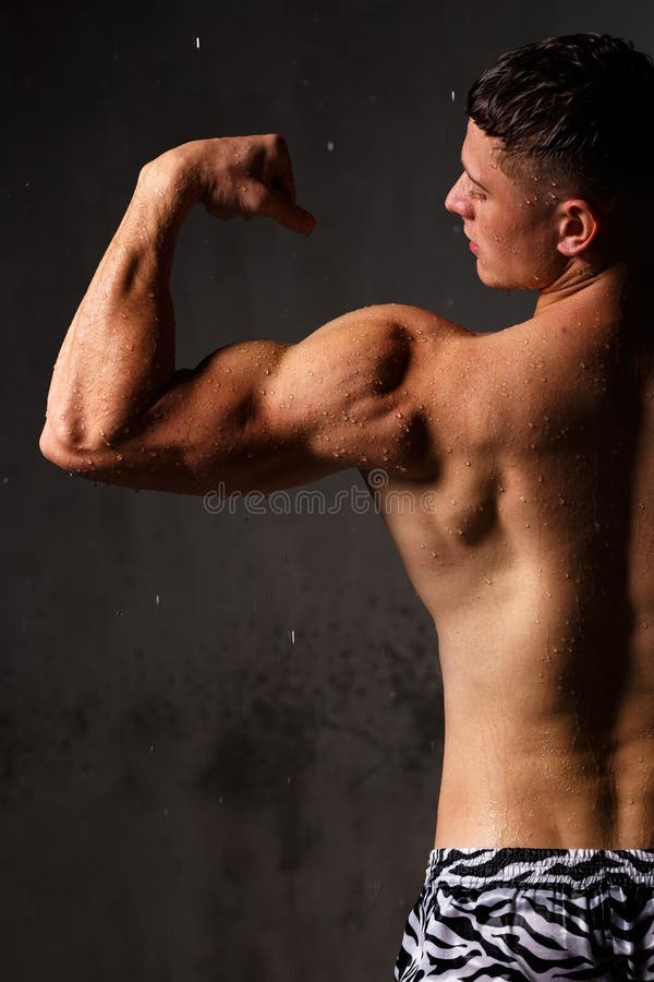 Athlete Bodybuilder Trains in the Studio in the Rain. Stock Photo