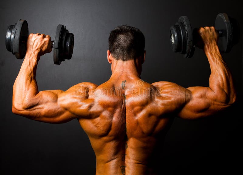 Rear view of bodybuilder training with dumbbells on black background