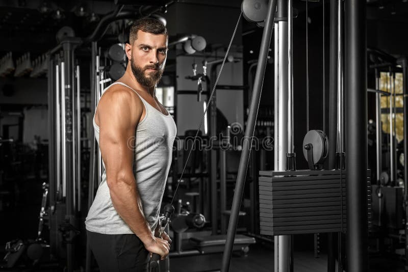 Bodybuilding. Bearded Man Standing Doingcable Straight Arm Pulldown at Gym Looking Camera