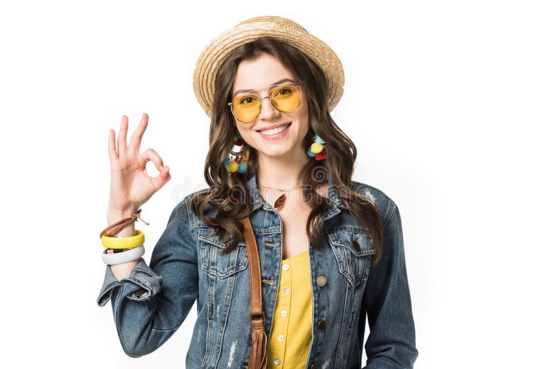 Smiling boho girl in boater and sunglasses showing okay sign isolated on white