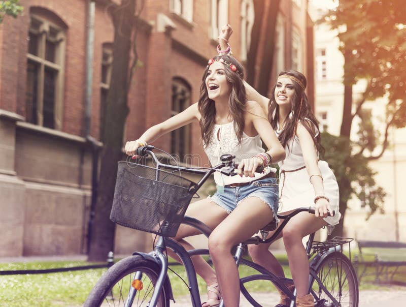 Happy hippie women riding a tandem in the park. Happy hippie women riding a tandem in the park