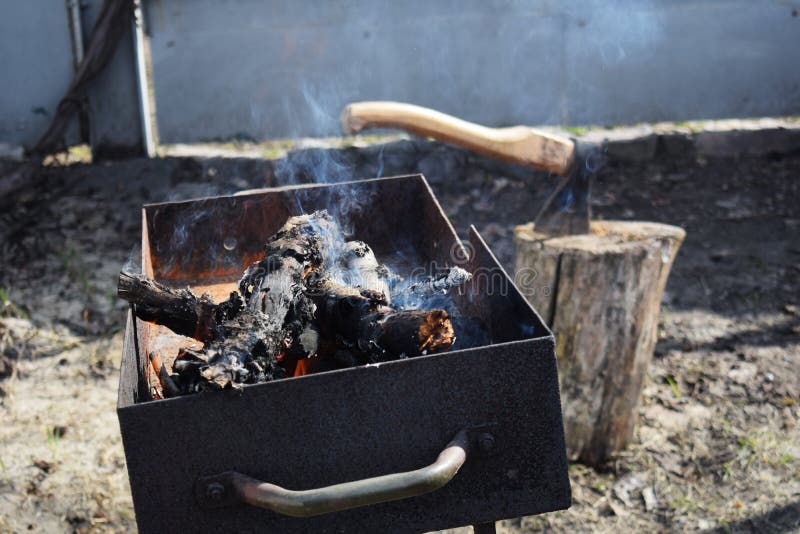 Bois de chauffage brûlant dans le vieux brasero avec une hache dans le tronçon à l'arrière-plan image libre de droits Bois de chauffage brûlant dans le vieux brasero avec une hache dans le tronçon à l'arrière-plan image libre de droits