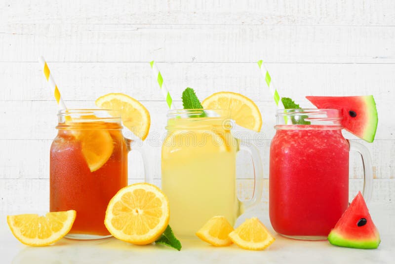 Boissons d'été de jus de thé glacé, de limonade et de pastèque en verres de pot de maçon contre le bois blanc photographie stock libre de droits Boissons d'été de jus de thé glacé, de limonade et de pastèque en verres de pot de maçon contre le bois blanc photographie stock libre de droits
