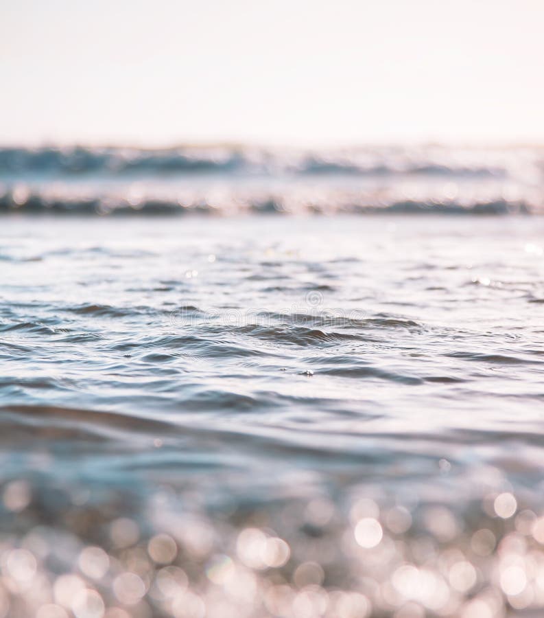 Ocean waves and surf with bokeh effects in the foreground. Image features soft, selective focus with subtle cross-processing. Ocean waves and surf with bokeh effects in the foreground. Image features soft, selective focus with subtle cross-processing.