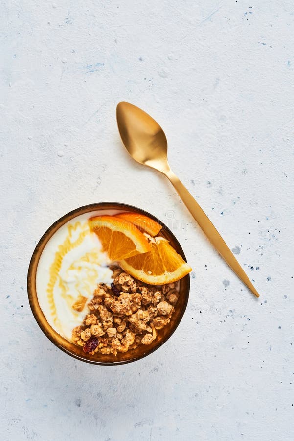Bol de granola faite maison avec du yaourt, le miel et l'orange fraîche photo stock Bol de granola faite maison avec du yaourt, le miel et l'orange fraîche photo stock