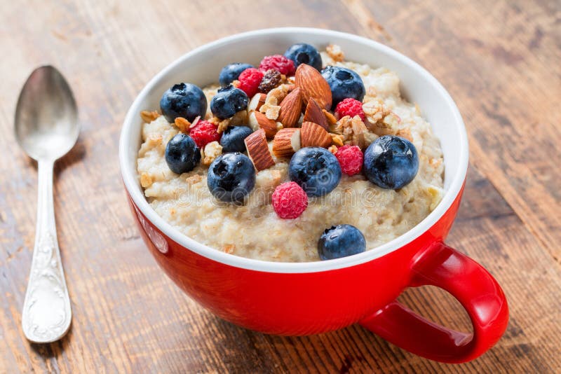 Bol de gruau de farine d'avoine avec des myrtilles, des framboises et le muesli photo stock Bol de gruau de farine d'avoine avec des myrtilles, des framboises et le muesli photo stock