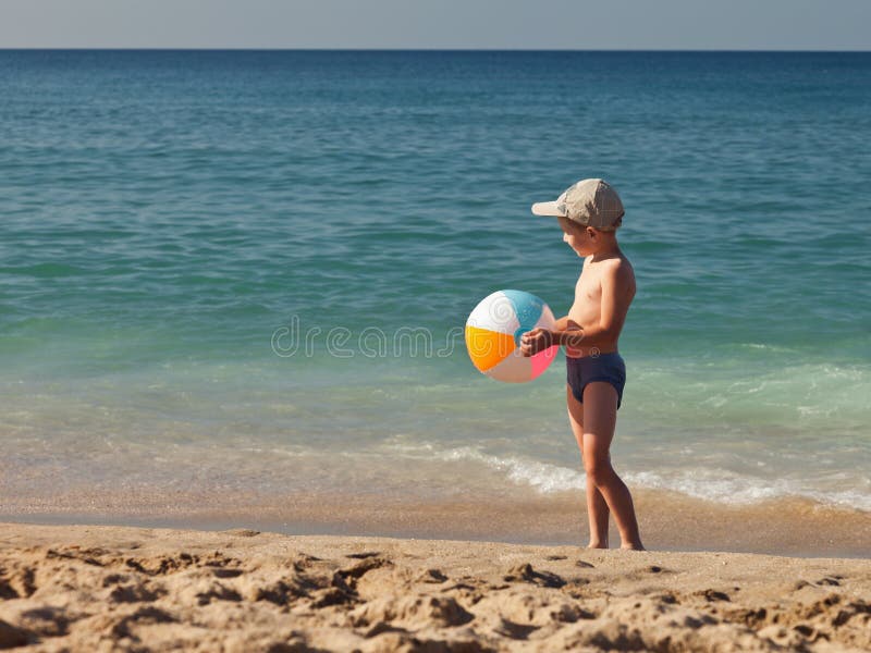 Bola de la explotación agrícola del muchacho en la playa del arena de mar foto de archivo libre de regalías Bola de la explotación agrícola del muchacho en la playa del arena de mar foto de archivo libre de regalías