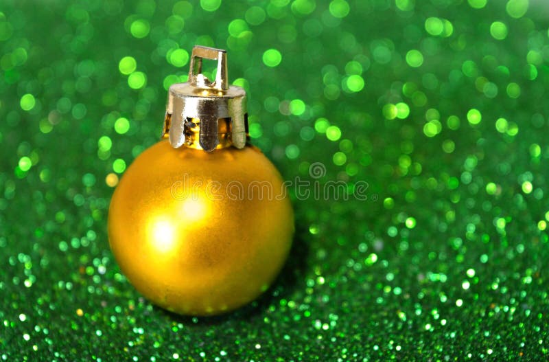 Bola de oro de la Navidad en fondo borroso del brillo verde imágenes de archivo libres de regalías Bola de oro de la Navidad en fondo borroso del brillo verde imágenes de archivo libres de regalías