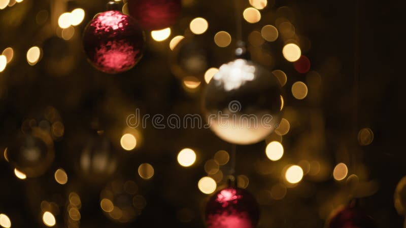Bolas de Natal a balançar em frente a uma árvore decorada filme