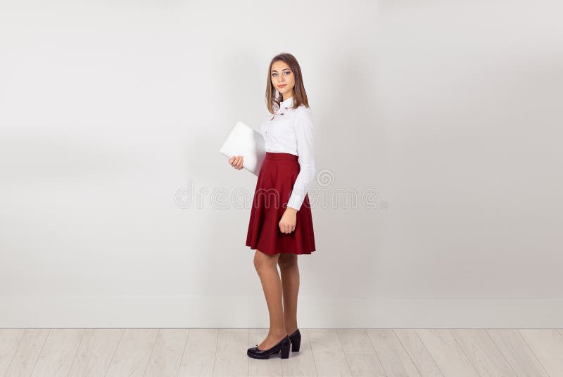 Bold and successful. Confident daydreaming girl holding grey laptop computer. Full length one person standing in profile. Isolated