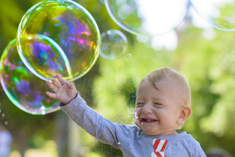 Cute baby catching soap bubbles in a summer day. Cute baby catching soap bubbles in a summer day