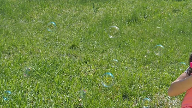 Bolhas do sopro da mamã e da filha Família no parque As crianças com mamã estão jogando com bolhas