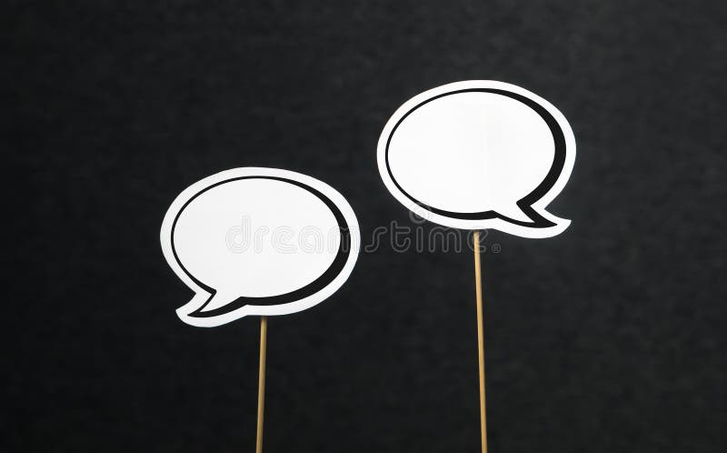 2 blank speech bubbles on a dark black background. Chat bubble cut from paper with wooden stick. Fun discussion, protesting and commenting concept with plenty of free copy space for your own text. 2 blank speech bubbles on a dark black background. Chat bubble cut from paper with wooden stick. Fun discussion, protesting and commenting concept with plenty of free copy space for your own text.