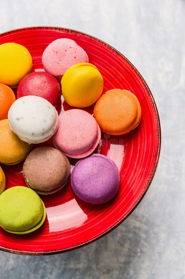 Bolinhos de amêndoa coloridos na placa vermelha no fundo de madeira cinzento foto de stock