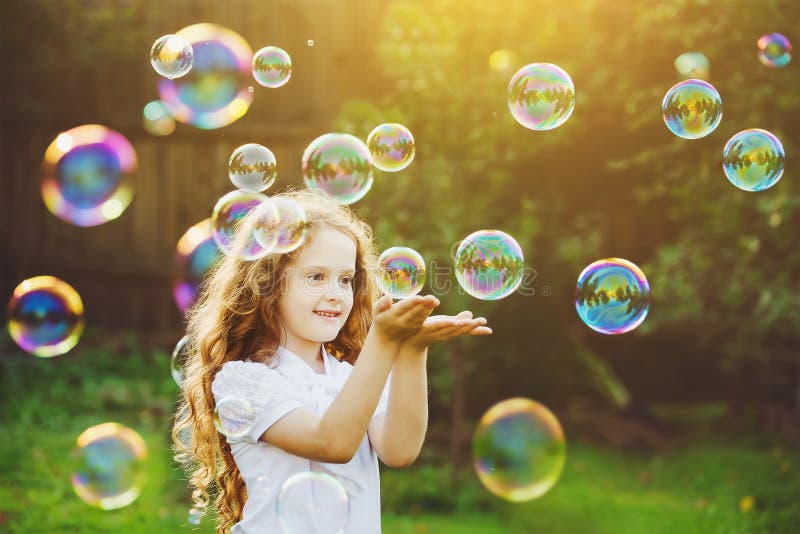 Bolle di sapone di cattura della bambina divertente di estate sulla natura fotografia stock Bolle di sapone di cattura della bambina divertente di estate sulla natura fotografia stock