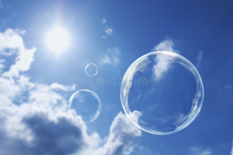 Bolle di sapone di galleggiamento contro chiari cielo blu e nuvole soleggiati