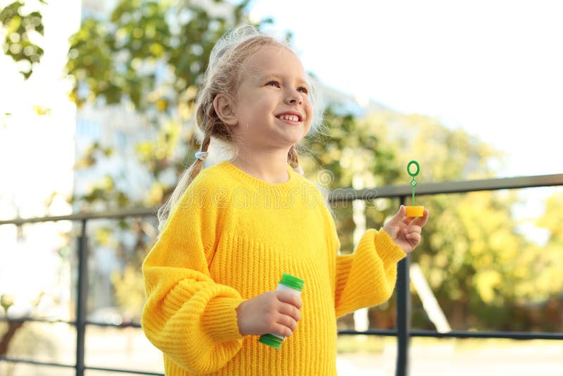 Bolle di sapone di salto della bambina sveglia fotografie stock Bolle di sapone di salto della bambina sveglia fotografie stock
