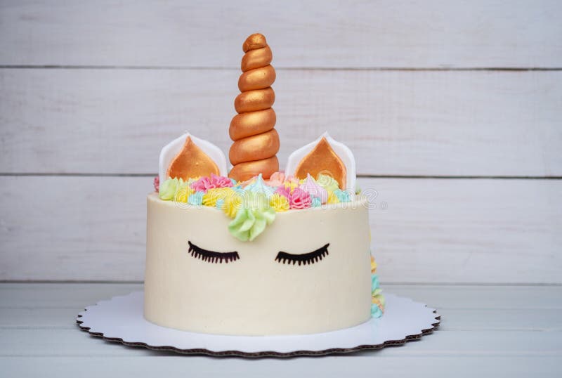 Bolo caseiro bonito na forma de um unicórnio no fundo de madeira branco imagem de stock Bolo caseiro bonito na forma de um unicórnio no fundo de madeira branco imagem de stock