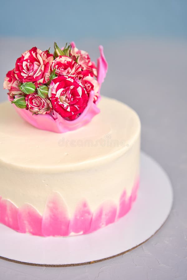 Bolo caseiro decorado com uma coroa de caramelo com um buquê natural de rosas sobre uma coluna de concreto leve contra uma parede imagem de stock royalty free Bolo caseiro decorado com uma coroa de caramelo com um buquê natural de rosas sobre uma coluna de concreto leve contra uma parede imagem de stock royalty free