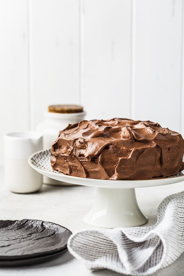 Bolo de chocolate inteiro caseiro com creme e caramelo do chocolate na placa do bolo, fundo branco fotografia de stock Bolo de chocolate inteiro caseiro com creme e caramelo do chocolate na placa do bolo, fundo branco fotografia de stock