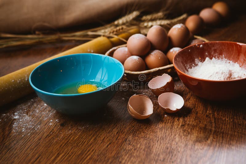 Bolo de cozimento na cozinha rural - ovos dos ingredientes da receita da massa, farinha, açúcar na tabela de madeira do vintage d