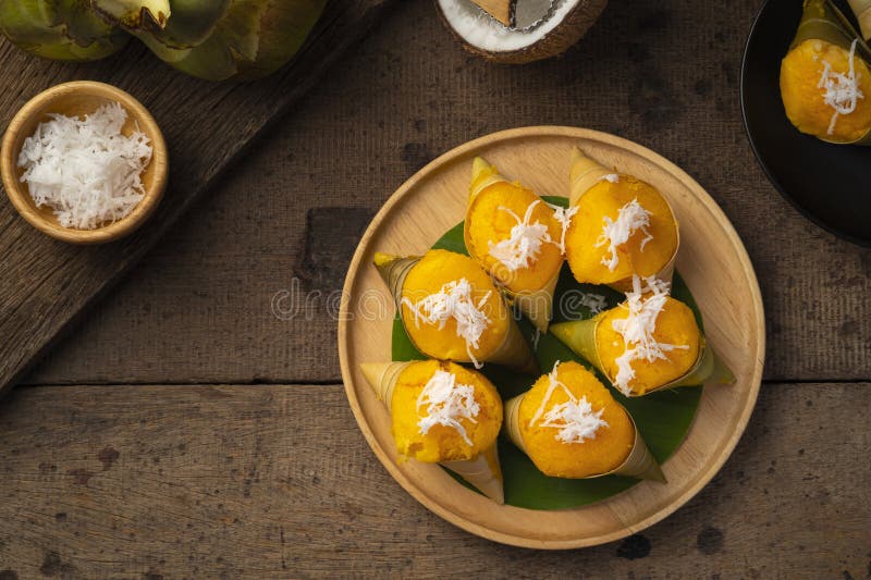 Toddy Palm Cake ,kind of like sponge cake,a little Sweet Yellow Thai cake in Toddy Palm leaf bowl on wooden plate.(Khanom Tan).Top view. Toddy Palm Cake ,kind of like sponge cake,a little Sweet Yellow Thai cake in Toddy Palm leaf bowl on wooden plate.(Khanom Tan).Top view